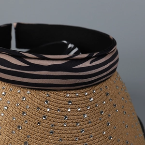 Detailed view of straw sun visor with zebra print ribbon and sparkling rhinestone accents