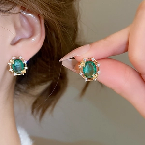 Detail of emerald oval stud earrings with 18k gold plating and small cubic zirconia