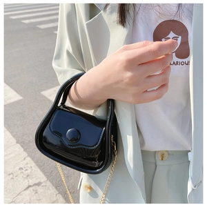 Chic black patent leather mini bag with gold chain strap shown in a street style view