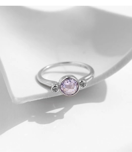 Détail d'une bague en argent avec une pierre ronde violette et des pierres latérales fines