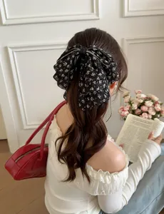 Macro detail of large black floral chiffon bow hair claw with pearl edge accents