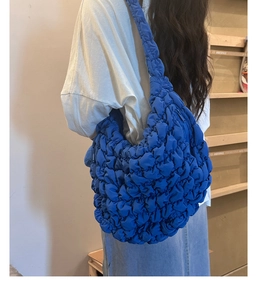 Detailed back view of a royal blue quilted cloud shoulder bag on a female model