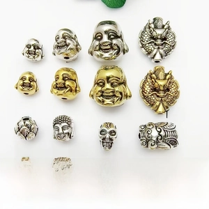 Macro display of 16 assorted metal beads featuring Buddha and skull motifs for DIY crafts