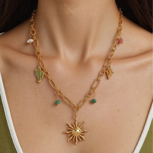 Gold chain necklace with shell star and cactus charms worn on woman neck for beach style