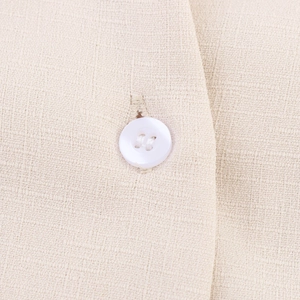Close-up of beige linen shirt fabric texture and a white four-hole button detail