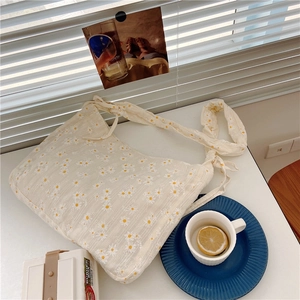 Detail of daisy floral canvas tote bag with wide knotted strap and cream background
