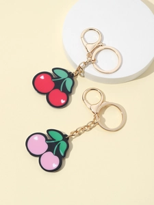 Detail view of red and pink cherry keychains with green leaves and golden hardware