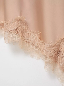 Close-up of elegant eyelash lace trim on apricot satin dress fabric detail