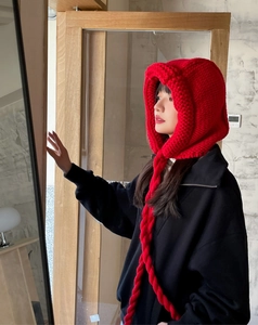 Détail de la cagoule rouge en maille épaisse avec texture de laine et longs liens