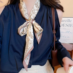 Close-up of a cream-colored silk scarf necklace with brown paisley prints on a model