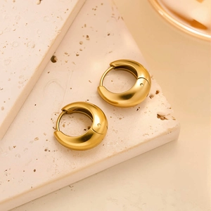 Détail de boucles d'oreilles créoles plaquées or 18k sur pierre blanche texturée