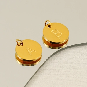 Polished golden stainless steel round pendants with engraved letters A and B detail