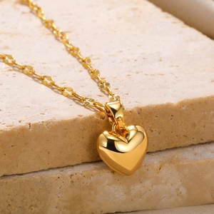 Macro shot of 18k gold plated heart pendant necklace on a natural stone surface