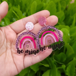 Rainbow-shaped acrylic earrings with pink leopard print and be mine text held in hand