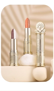 Detailed macro view of dual-color eye shadow sticks with ornate golden relief carvings