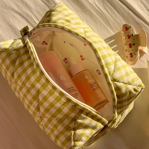 Inside view of green plaid quilted cosmetic bag with red cherry print lining