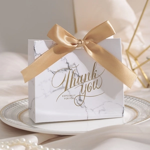 Detail of white marble wedding gift box with champagne gold ribbon and Thank You text