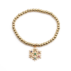 Détail d'un bracelet doré à billes avec pendentif flocon de neige en zircon coloré brillant