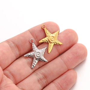 Macro shot of gold and silver starfish pendants with hammered texture and spiral center