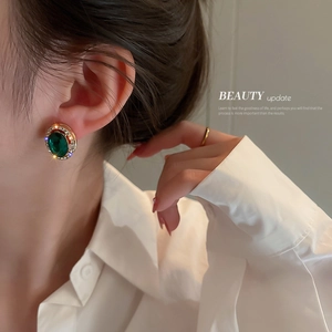 Orecchini vintage con cristallo smeraldo, bordo dorato e strass su una modella