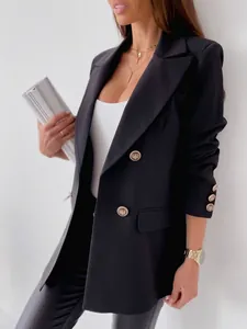 Detail of a black double-breasted blazer showing embossed gold buttons and flap pockets