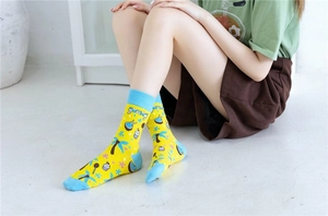 Gros plan de chaussettes en maille jaune avec motifs cocotier et cupcake et texte 'yummy'