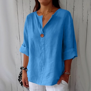 Dettaglio top blu in cotone e lino con scollo a V, bottone e trama delle maniche