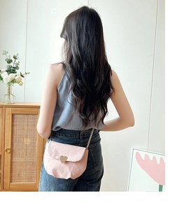 Gros plan sur un sac selle rose en forme de cœur avec chaîne dorée sur un mannequin