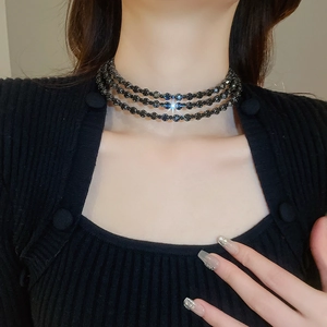 Detail of three-layer black beaded choker necklace with starburst sparkle on model