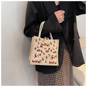 Close-up of floral beige canvas bag with woven rope handles and a wooden decorative button