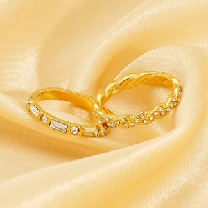 Golden twist ring set with rectangular zircons on minimalist beige velvet background