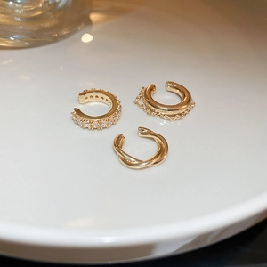 Detailed close-up of three-piece gold ear cuff set with pavé zircon on white ceramic