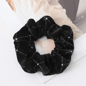 Macro detail of black velvet scrunchie with silver glitter sequins in a geometric pattern
