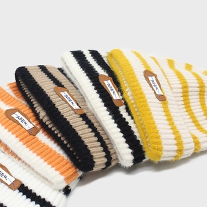 Detail of colorful striped knit beanies with ribbed texture and brown leather patch