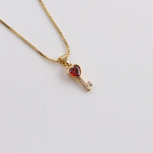 Detail of gold-plated key necklace featuring a red heart crystal and white zircon stones