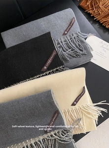 Detail of soft cashmere-feel scarves with fringe and leather label in multiple autumn colors