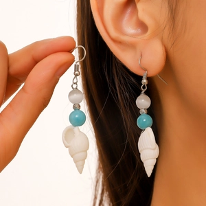 Detail of seashell earrings with natural blue stones and pearls for beach vacation