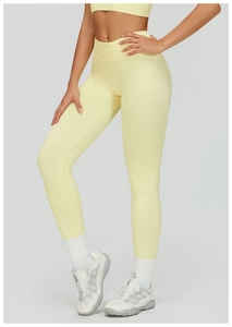 Detail of high-waist seamless yoga leggings and sports bra in pale yellow knit fabric