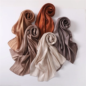 Detailed view of glossy satin scarves in bronze, caramel, and silver metallic tones