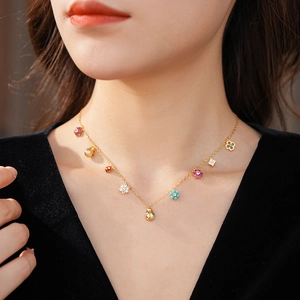 Close-up of a gold necklace featuring colorful enamel flower and ladybug charms on a neck