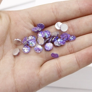 Macro shot of 6mm purple iridescent fish scale resin cabochons held in hand for DIY jewelry