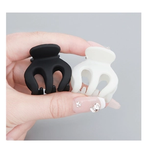 Mini matte claw clips in black and beige showing 3-prong design and smooth texture