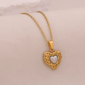 Close-up of golden heart pendant with iridescent gemstone inlay and hammered metal texture