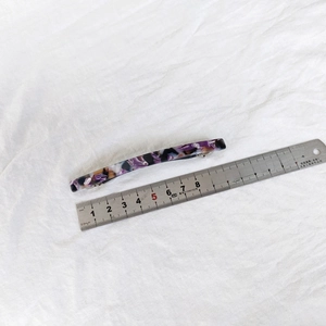 Macro view of 8cm tortoiseshell acetate hair clip on fabric with ruler for size detail