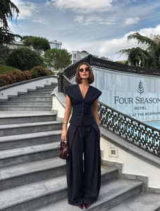 Close-up of women's pinstripe vest and wide-leg trousers suit with a burgundy bucket bag