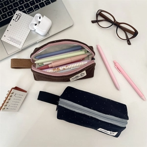 Close-up of minimalist polka dot felt pencil cases in coffee and navy blue finishes