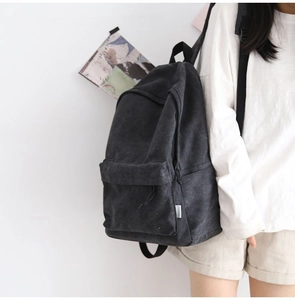 Detailed view of durable dark gray canvas backpack worn by a model in a minimalist setting