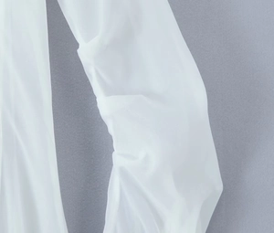 Detail shot of white V-neck dress featuring sheer textured fabric and pleated sleeve
