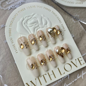 Detailed view of handmade pink gradient press-on nails with heart rhinestones on display card