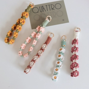 Close-up of five handmade woven floral phone charms in various colors with gold rings